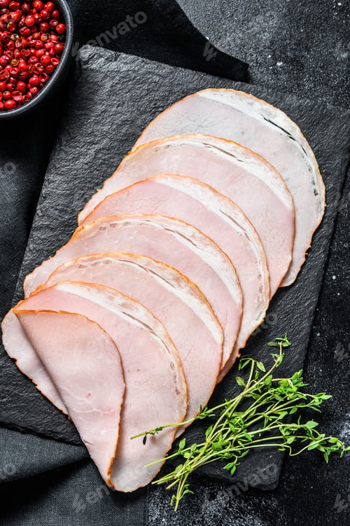 Preview: Slices of pork ham with thyme. Organic meat. Black background. Top view.
