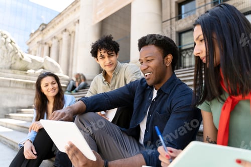 Preview: Students collaborating on project using digital tablet on university steps
