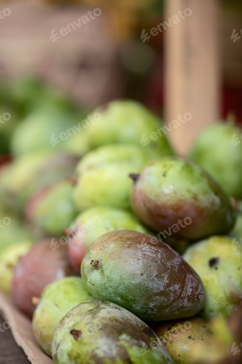Preview: tropical fruits, green mango fruits, on the counter of a roadside shop, selective focus