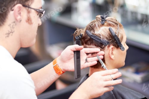 Preview: Giving her the perfect cut. A young woman getting a haircut at the hairdresser.