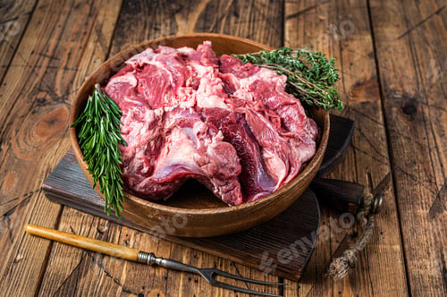 Preview: Boneless raw mutton Lamb Shoulder meat in wooden plate with herbs. wooden background. Top view