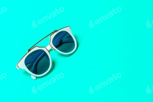 Preview: Sunglasses lying on a bright background with reflections on lenses