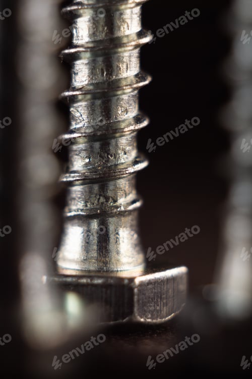 Preview: Vertical shot of different screws and bolts on a rough surface