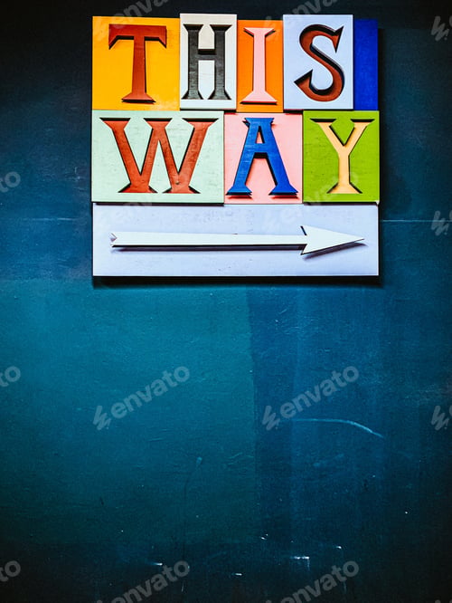 Preview: Closeup shot of colourful THIS WAY and arrow pointing right on the blue background