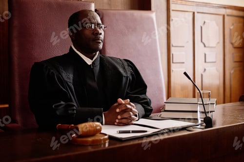 Preview: Serious male impartial judge in uniform sitting by desk in front of microphone
