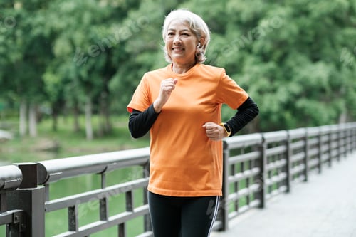 Preview: Athletic Senior woman running outdoor jogging in park.
