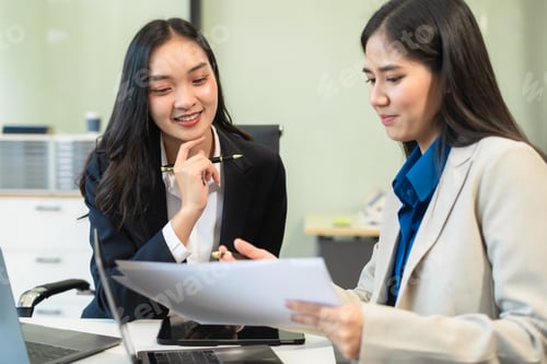 Preview: Asian manager mentor talking to young Asian female coworker, showing online project