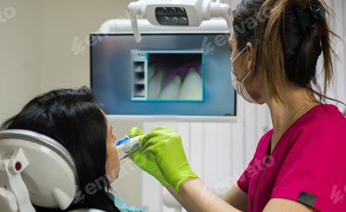 Preview: Dentist examining woman's teeth with camera