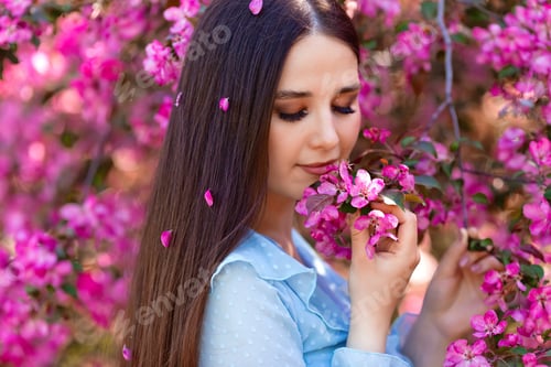 Preview: A beautiful brunette girl with pink petals in her long hair