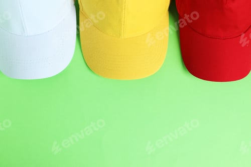 Preview: Colorful baseball hats on light green background, top view. Space for text