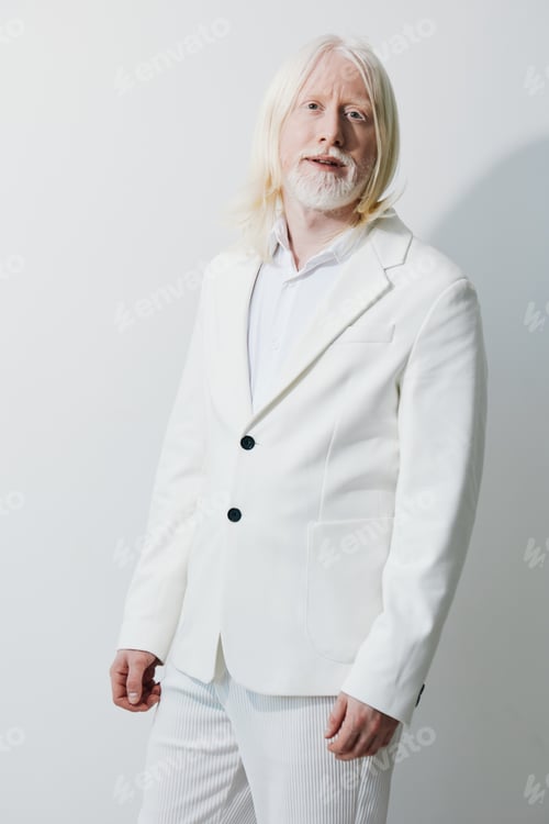 Preview: Elegant man in a stylish white suit with long hair standing against a light background, exuding