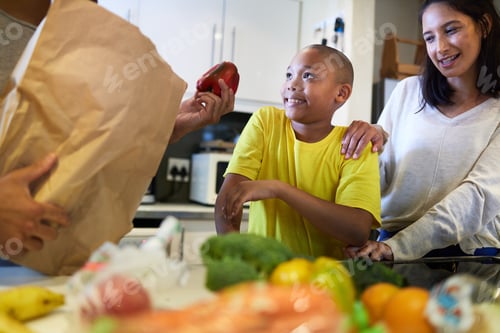 Preview: Whats for supper. Shot of a family unpacking the groceries in the kitchen at home.