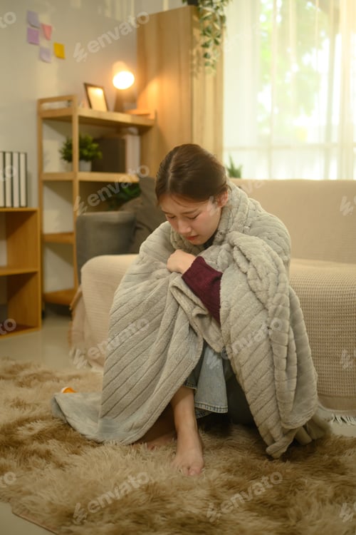 Preview: Sick woman wrapped in blanket, suffering from fever or flu