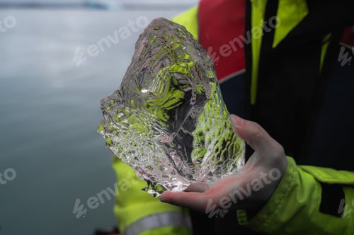 Preview: Closeup of person holding part of clear iceberg in hand