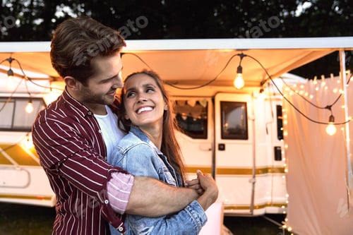 Preview: Young couple hugging and camper in the background