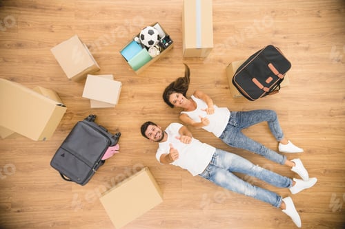 Preview: The happy couple rest on a floor and gesture near carton boxes. view from above