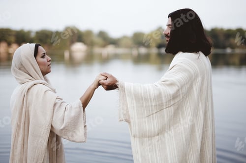 Preview: Shallow focus shot of a female wearing a biblical robe and holding the hand of Jesus Christ
