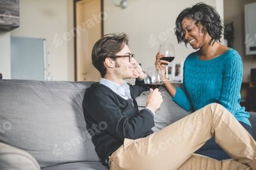 Preview: Young handsome mixed race couple in their house having a glass of red wine
