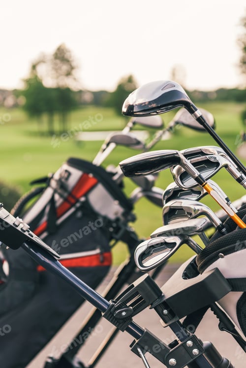Preview: Close-up view of shiny golf clubs in golf bags outdoors