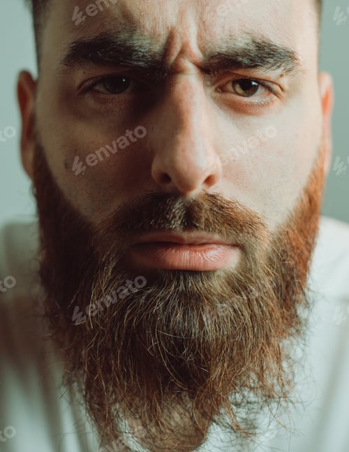 Preview: Portrait of a young bearded man looking very close to the lens. Funny image