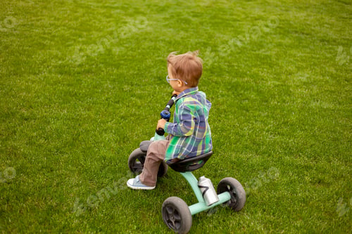 Preview: Child rides a bike on lawn in the backyard