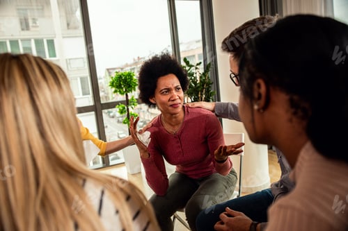 Preview: Diverse group of people sitting in circle in group therapy session.