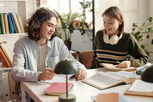 Preview: Two Smiling Students Studying at Desk in College Class Reading Textbooks