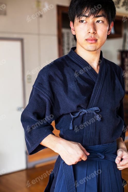 Preview: Male Japanese Kendo fighter tying belt of his blue Kendo uniform.