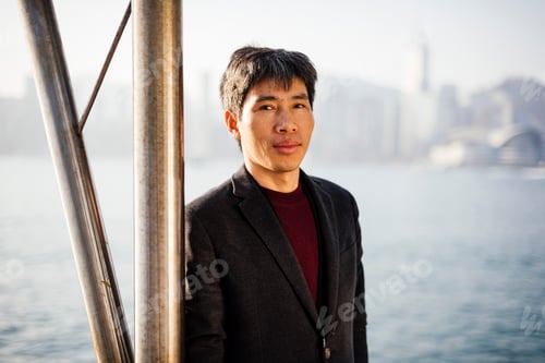 Preview: Man in business casual attire stands confidently with a cityscape backdrop.
