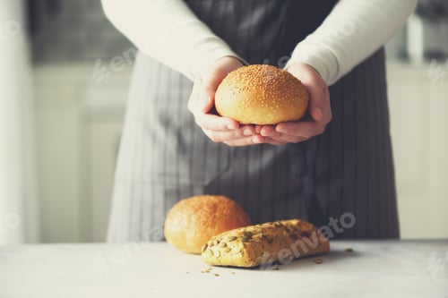 Preview: Woman hands holding freshly baked bread. Bun, cookie, bakery concept, homemade food, healthy eating