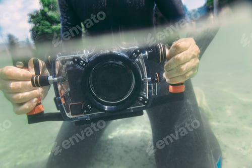 Preview: Man holding underwater DSLR camera case in a lake