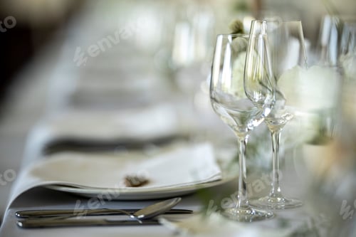 Preview: Closeup of a festive table with white dishes and glasses, blurred background