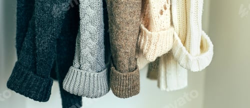 Preview: Knitted clothes sweater hanging in the closet. Cozy autumn-winter wardrobe. Banner image