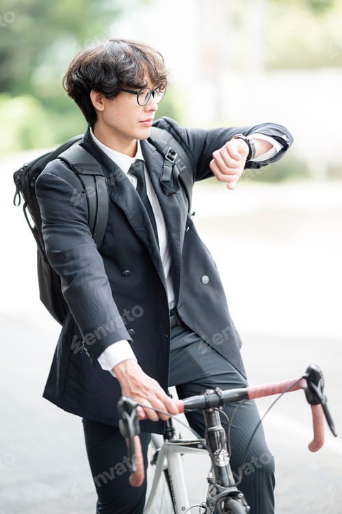 Preview: Man sitting on a bicycle look at the time on the wristwatch.