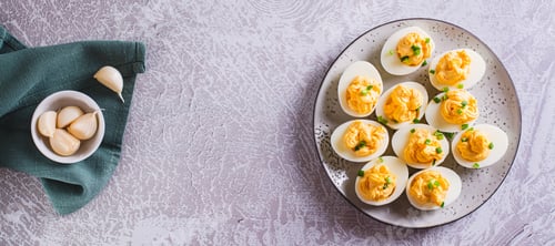 Preview: Boiled eggs stuffed with yolk, cheese, garlic and mayonnaise on a plate top view web banner