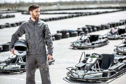 Preview: Smiling Man Stands Near Go-Karts Holding Helmet
