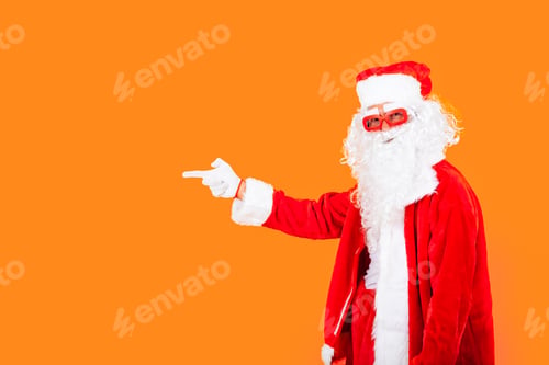 Preview: cool modern santa claus on orange background pointing to the copy space