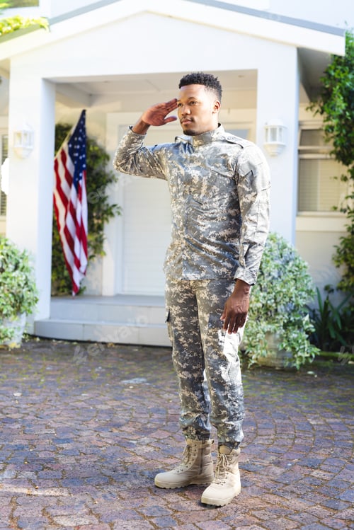 Preview: Focused african american male soldier standing and saluting outside home with usa flag, copy space