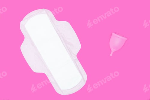 Preview: menstrual cup and regular feminine pad on a pink background, top view,copy space.Zero waste concept