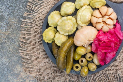 Preview: A dark plate full of cabbage and pickled cucumbers