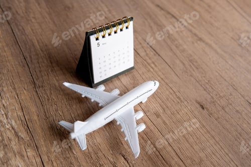 Preview: Toy airplane on a wooden table next to a calendar.
