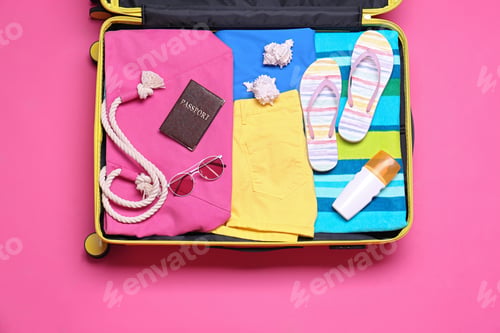 Preview: Open suitcase with beach objects on pink background, top view