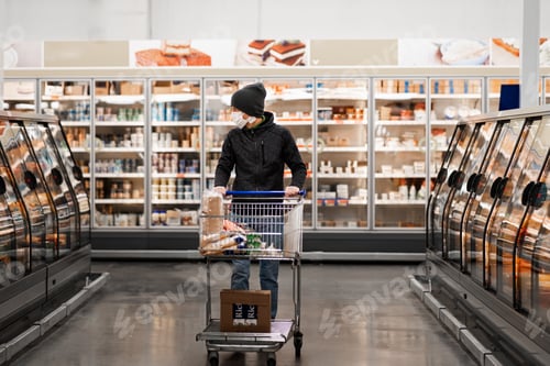 Preview: New normal. Adult man in protective mask and gloves select foods at the store center during covid