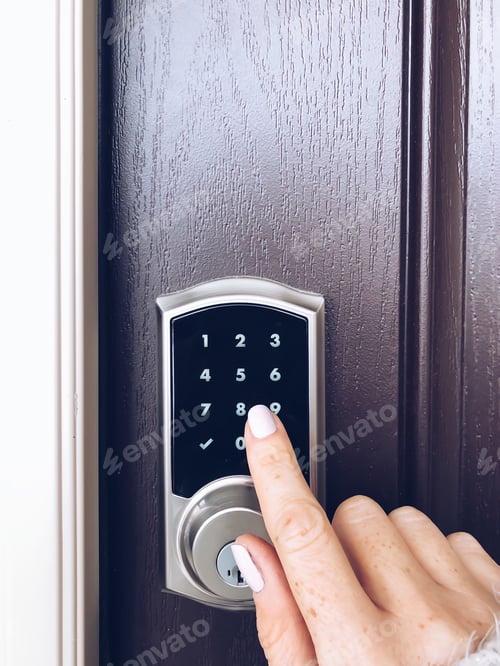 Preview: Woman’s hand is pressing numbers on an electronic keypad to open the door of a house
