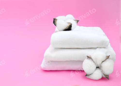 Preview: Cotton plant and white folded fabric on pink background. Cotton clothes fabric concept. Minimalism a