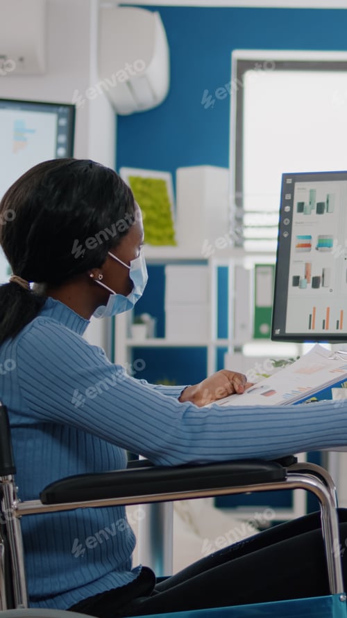 Preview: Black woman with disabilities and protection face masks working on computer
