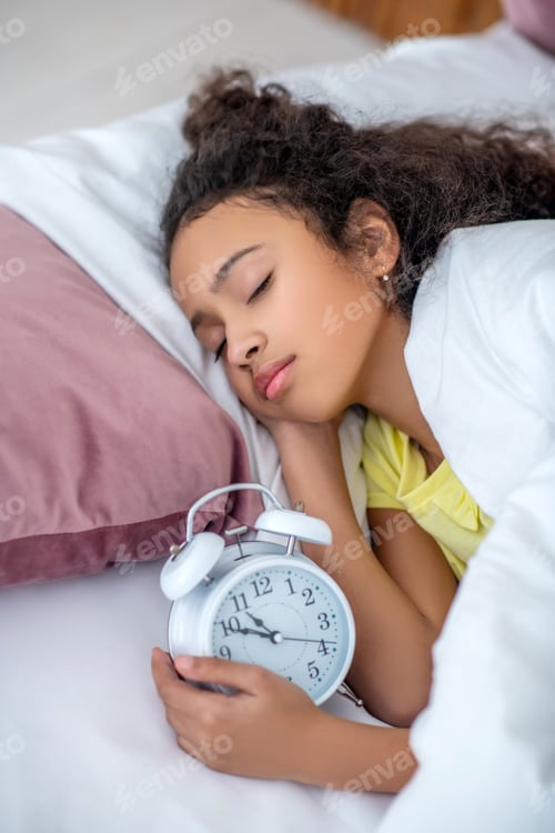 Preview: Dark-haired teenage girl sleeping at home in bed.