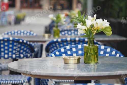 Preview: Outdoor cafe tables with flowers in a city setting during daytime
