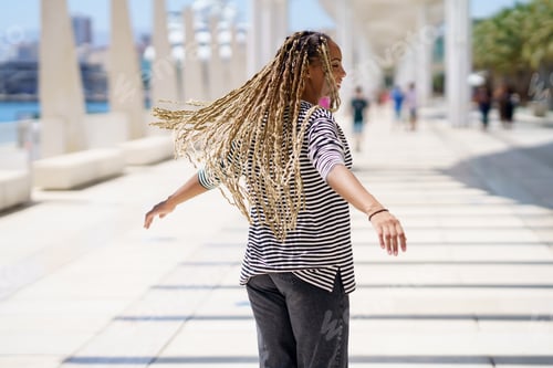 Preview: Young black female moving her coloured braids in the wind. Typical African hairstyle.