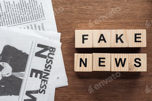 Preview: top view of wooden cubes with words fake news and newspapers on wooden tabletop